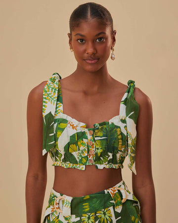 model wearing white cropped tank top with tie straps, ruffle detail and green tropical leaf print