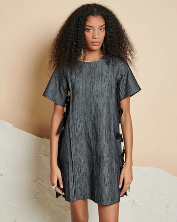 model wearing black washed mini dress with short sleeves and black bows down the sides