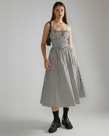 model wearing black and white gingham midi dress with large banded waist and ties on the neckline