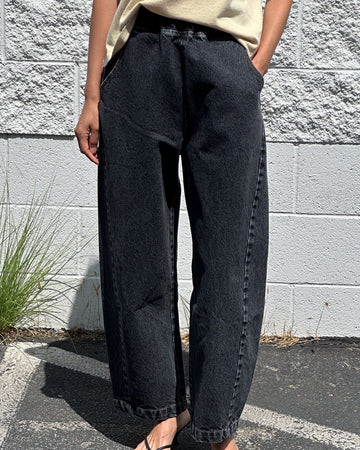 model wearing washed black arc pants with elastic waist, pockets, and barrel legs