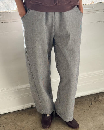 model wearing thin vertical white and navy stripes arc pants