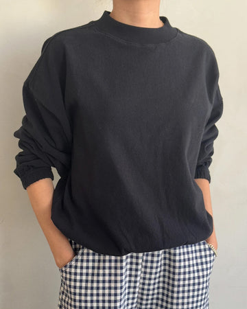 model wearing black long sleeve top with mock neck neckline and elastic sleeve cuffs and bottom