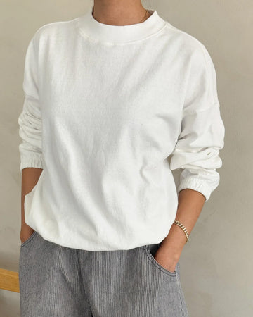 model wearing white long sleeve top with mock neck neckline and elastic sleeve cuffs and bottom