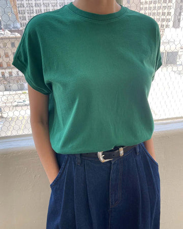 model wearing deep green cotton tee with slight capped sleeves and ribbed neckline