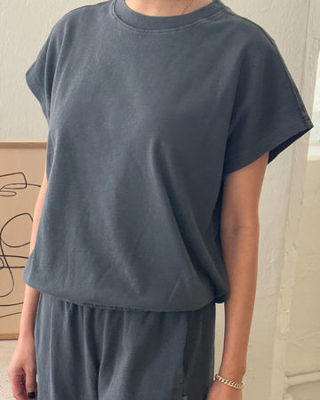 model wearing coal tee with slight cap sleeves, relaxed fit, and banded bottom