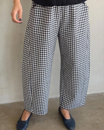 model wearing navy and white gingham arc pants with elastic waist, pockets, and barrel legs