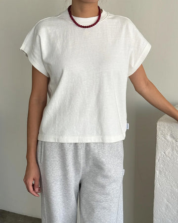 model wearing white relaxed tee with muscle tee sleeves and side vents at the hem