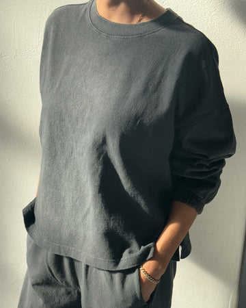 model wearing coal relaxed fit long sleeve top with ribbed neckline and cuffed sleeves