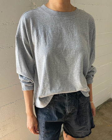 model wearing heather grey relaxed fit long sleeve top with ribbed neckline and cuffed sleeves