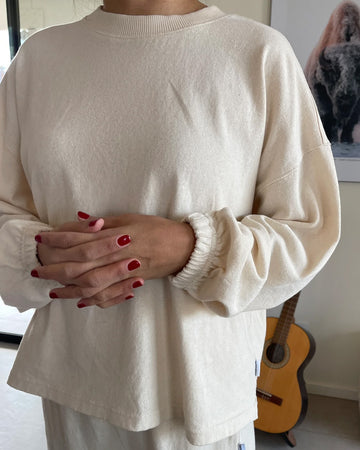 model wearing naturel relaxed fit long sleeve top with ribbed neckline and cuffed sleeves