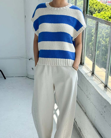 model wearing bright blue and cream striped sweater top with slight cap sleeves