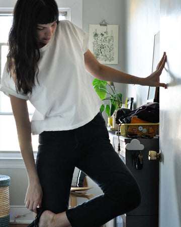 model wearing relaxed, slightly cropped clean white tee with distressing on the neckline