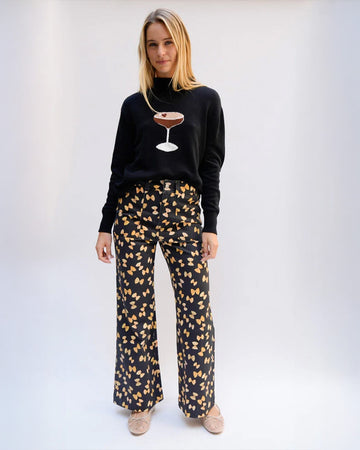 model wearing black flare pants with patch front pockets and all over bow tie pasta print