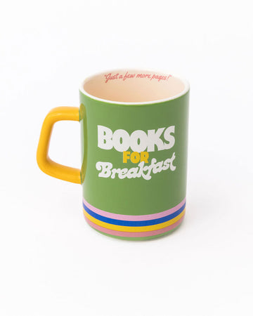 green ceramic mug with yellow handle, rainbow stripe bottom, 'books for breakfast' across the front and 'just a few more pages!' in the inside