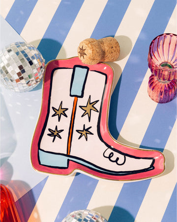 pink trinket tray with white and blue boot with star details in blue and white stripe table