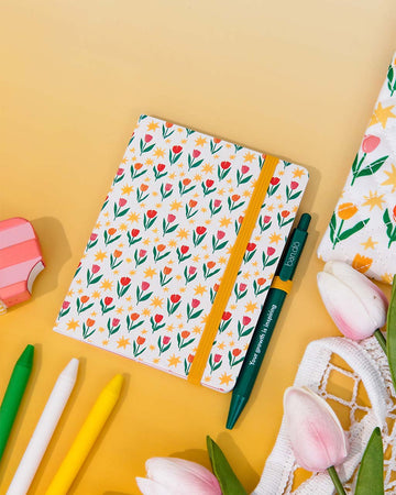 cream mini notebook with floral and star print with yellow elastic and green ban.do pen that says 'your growth is inspiring'