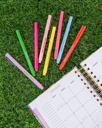 8 felt tip pen set with inspiring sayings on the side scattered in the grass